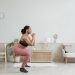 Woman in activewear doing squats at home, promoting a healthy lifestyle and fitness routine.